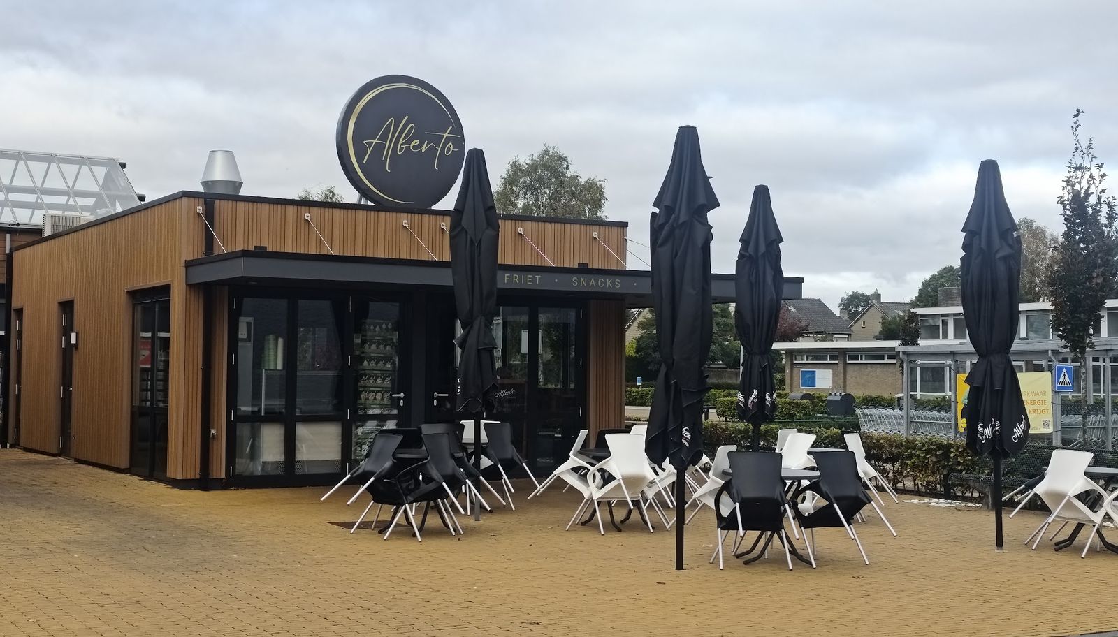 Het paviljoen met het ronde Alberto-bord, dichte parasols en terrasstoelen