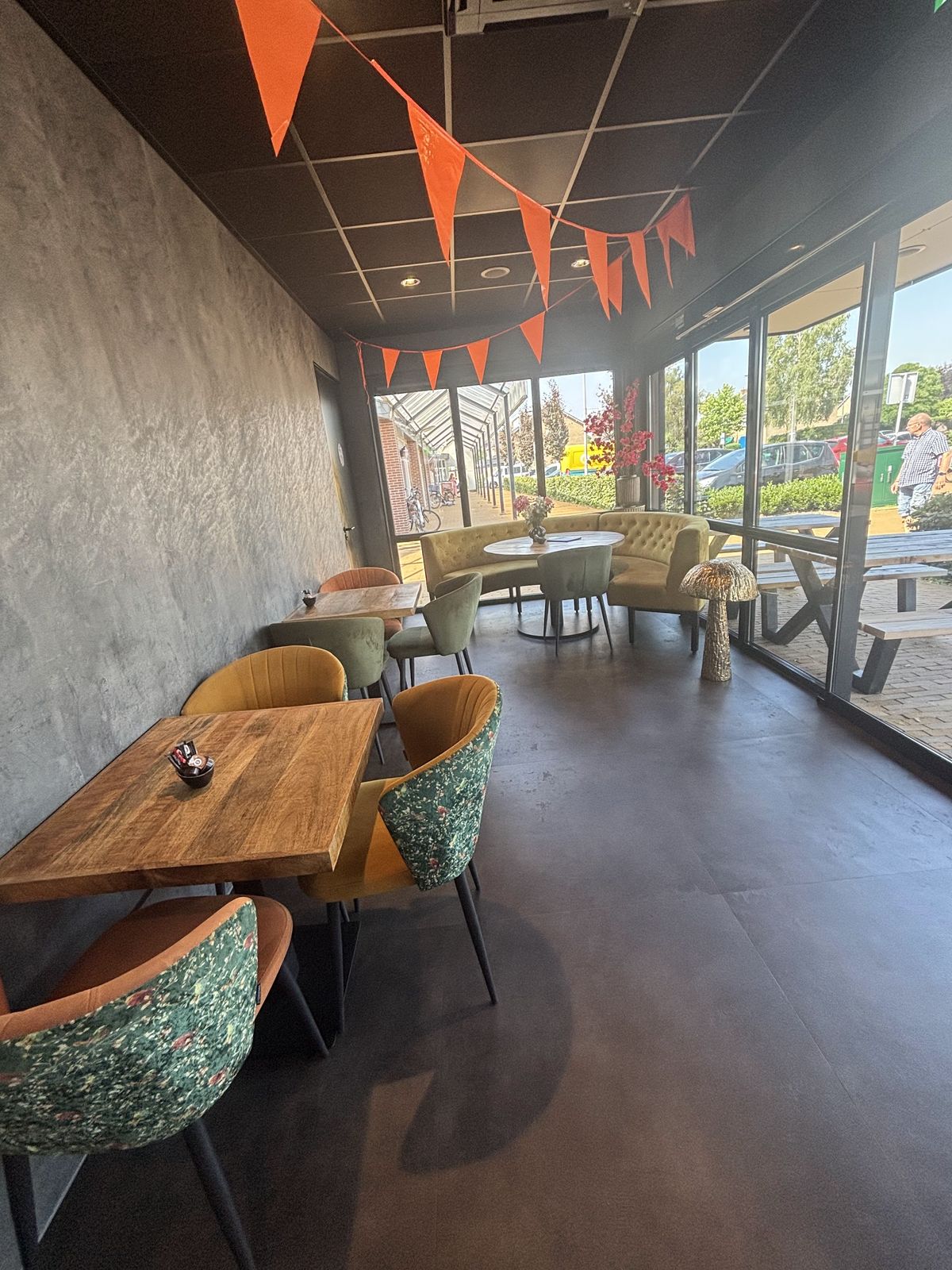 Zitjes met houten tafels en fluwelen stoelen langs de glazen pui