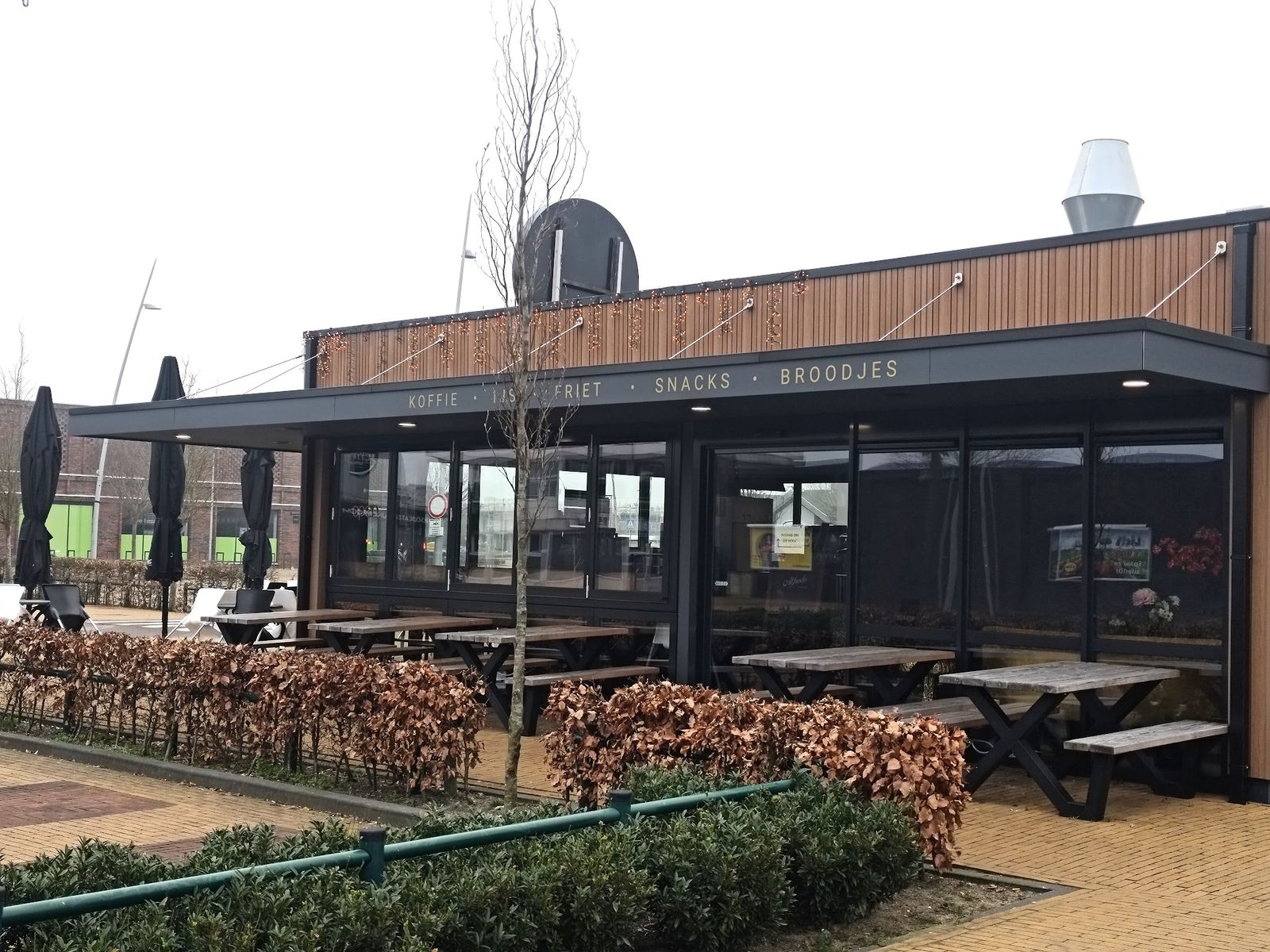De lange zijde van het paviljoen met de gevelband koffie, ijs, friet, snacks, broodjes en picknicktafels